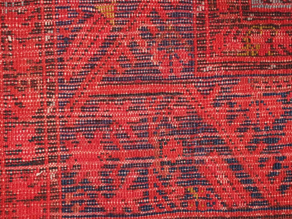 An antique hand-knotted Turkish Komurcu Kula wool rug featuring a central diamond medallion in crimson red, deep blue, dark brown, and grey-blue tones. View XIII