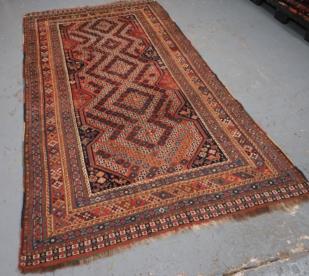 An antique Qashqai hand-knotted wool rug featuring a red and navy diamond lattice pattern with multi-band geometric borders. View II