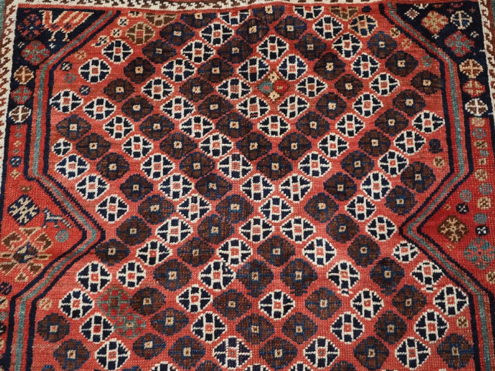 An antique Qashqai hand-knotted wool rug featuring a red and navy diamond lattice pattern with multi-band geometric borders. View IX