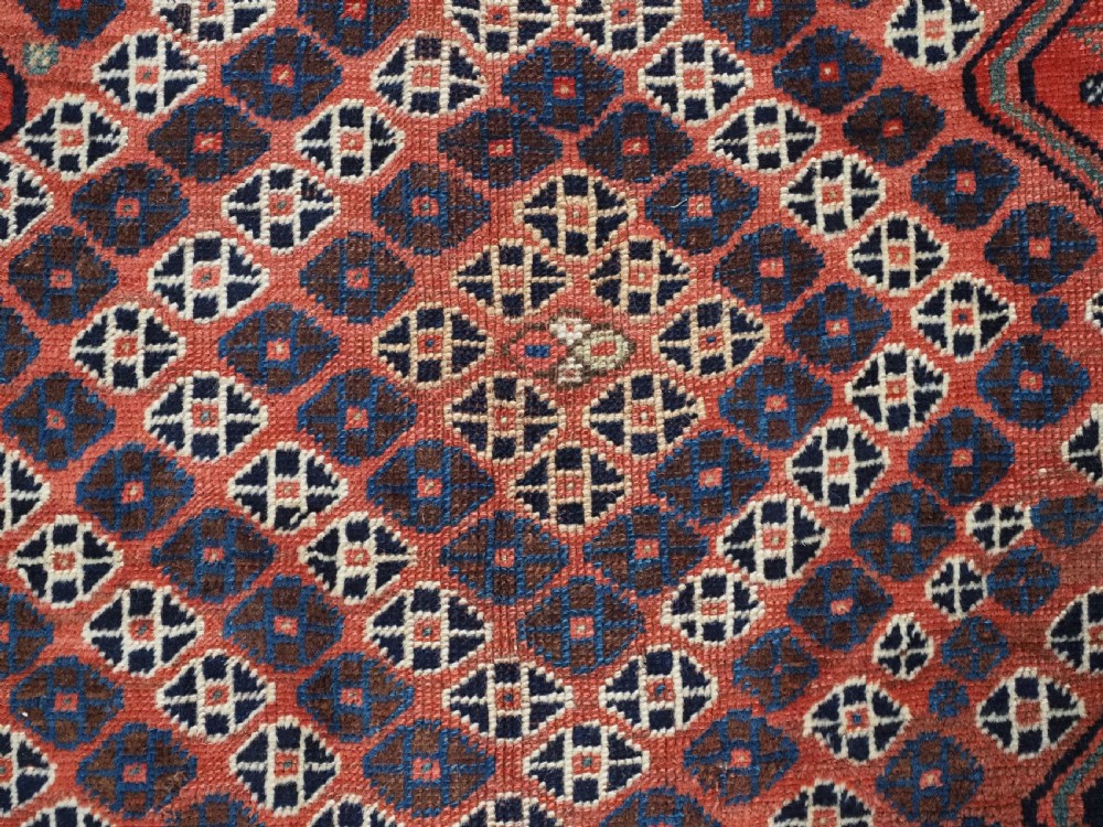 An antique Qashqai hand-knotted wool rug featuring a red and navy diamond lattice pattern with multi-band geometric borders. View XI