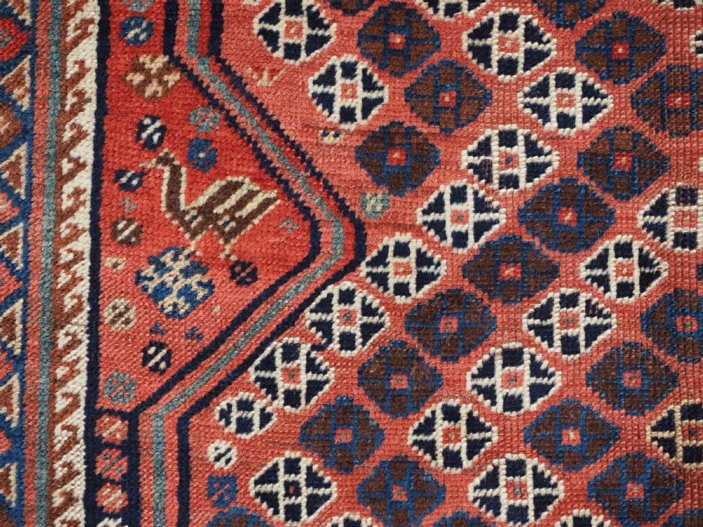An antique Qashqai hand-knotted wool rug featuring a red and navy diamond lattice pattern with multi-band geometric borders. View XII