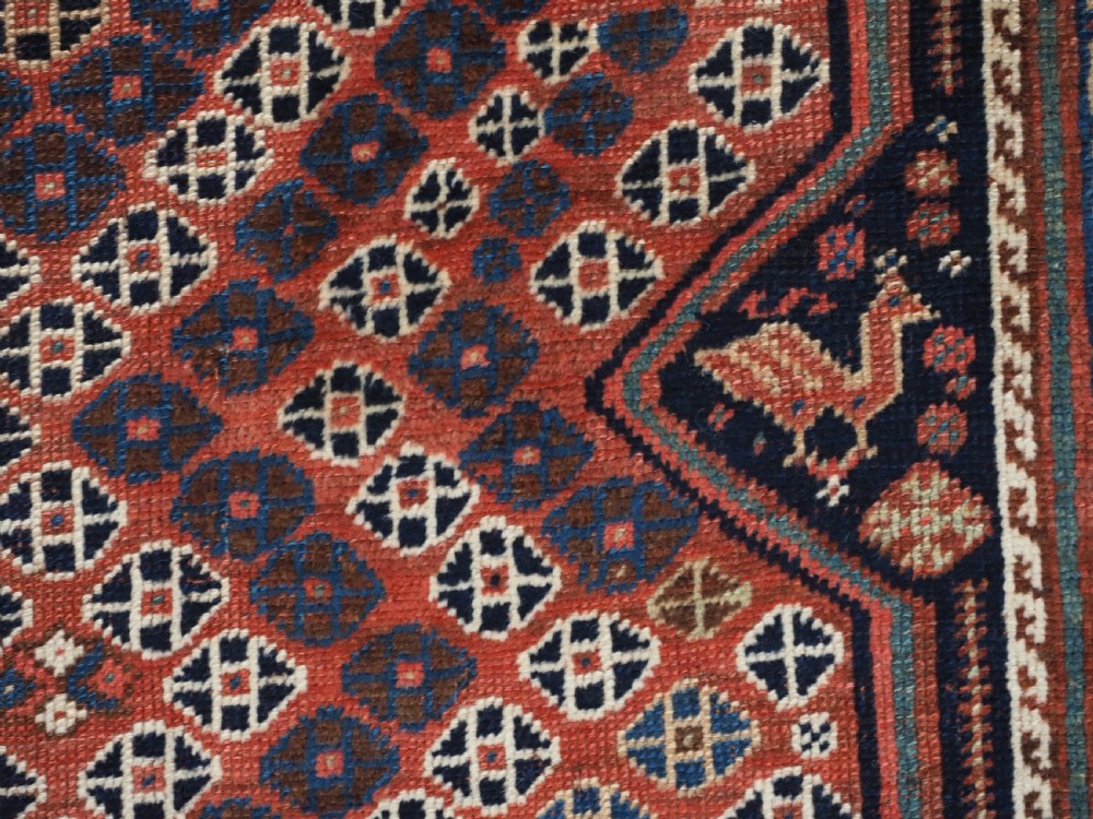 An antique Qashqai hand-knotted wool rug featuring a red and navy diamond lattice pattern with multi-band geometric borders. View XIII