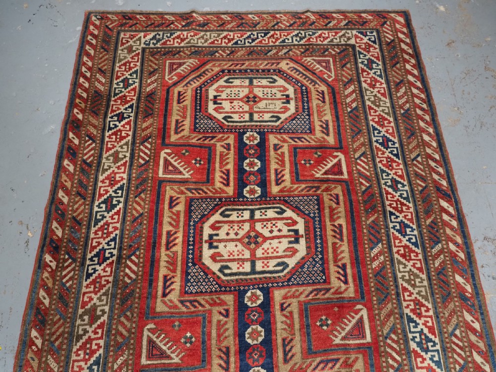 An antique Caucasian Shirvan long wool runner rug featuring terracotta red, navy blue, and beige octagonal geometric medallions within patterned borders. View III