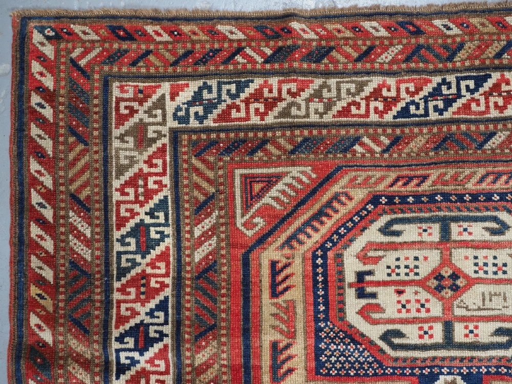 An antique Caucasian Shirvan long wool runner rug featuring terracotta red, navy blue, and beige octagonal geometric medallions within patterned borders. View VI