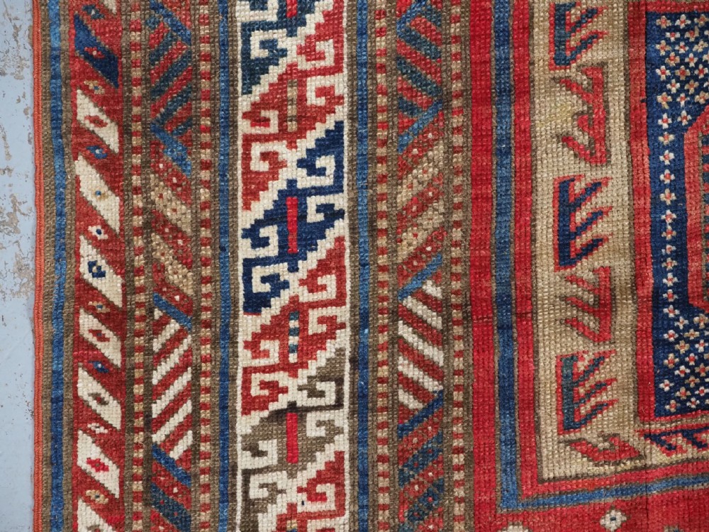An antique Caucasian Shirvan long wool runner rug featuring terracotta red, navy blue, and beige octagonal geometric medallions within patterned borders. View VII