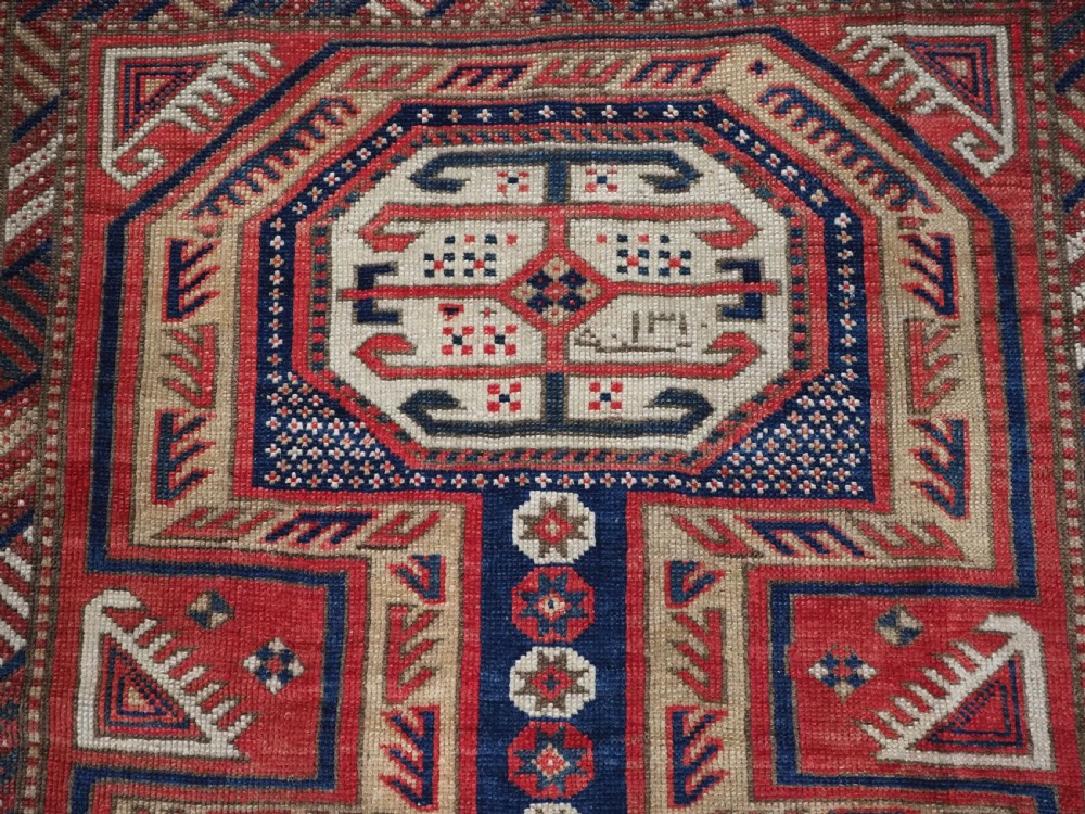 An antique Caucasian Shirvan long wool runner rug featuring terracotta red, navy blue, and beige octagonal geometric medallions within patterned borders. View VIII