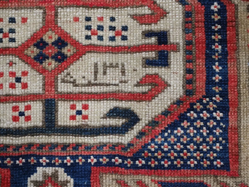 An antique Caucasian Shirvan long wool runner rug featuring terracotta red, navy blue, and beige octagonal geometric medallions within patterned borders. View IX