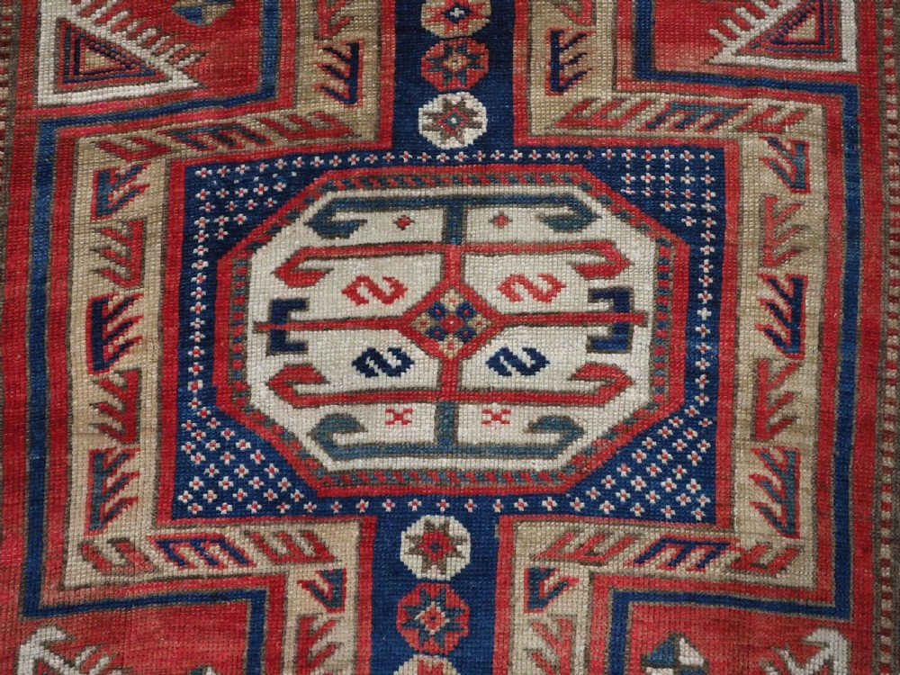 An antique Caucasian Shirvan long wool runner rug featuring terracotta red, navy blue, and beige octagonal geometric medallions within patterned borders. View XII