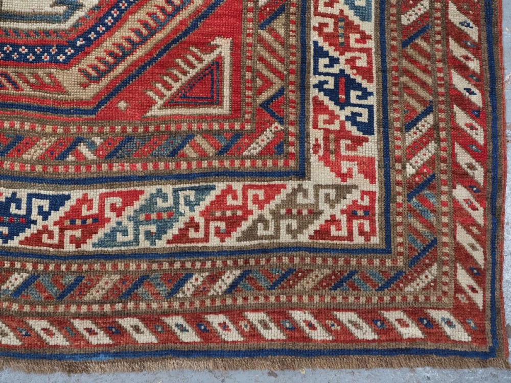 An antique Caucasian Shirvan long wool runner rug featuring terracotta red, navy blue, and beige octagonal geometric medallions within patterned borders. View XIV