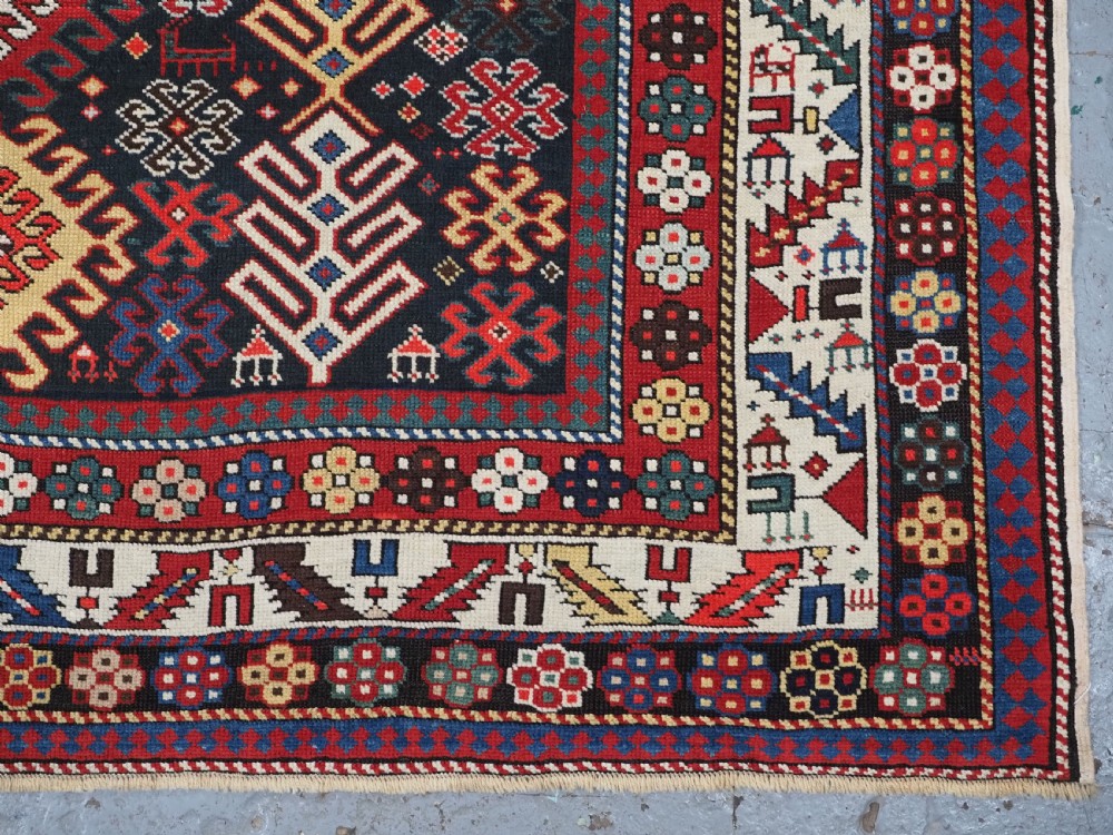 An antique long Caucasian runner rug featuring a dark navy field filled with multi-coloured hooked diamond medallions and detailed geometric borders. View XII