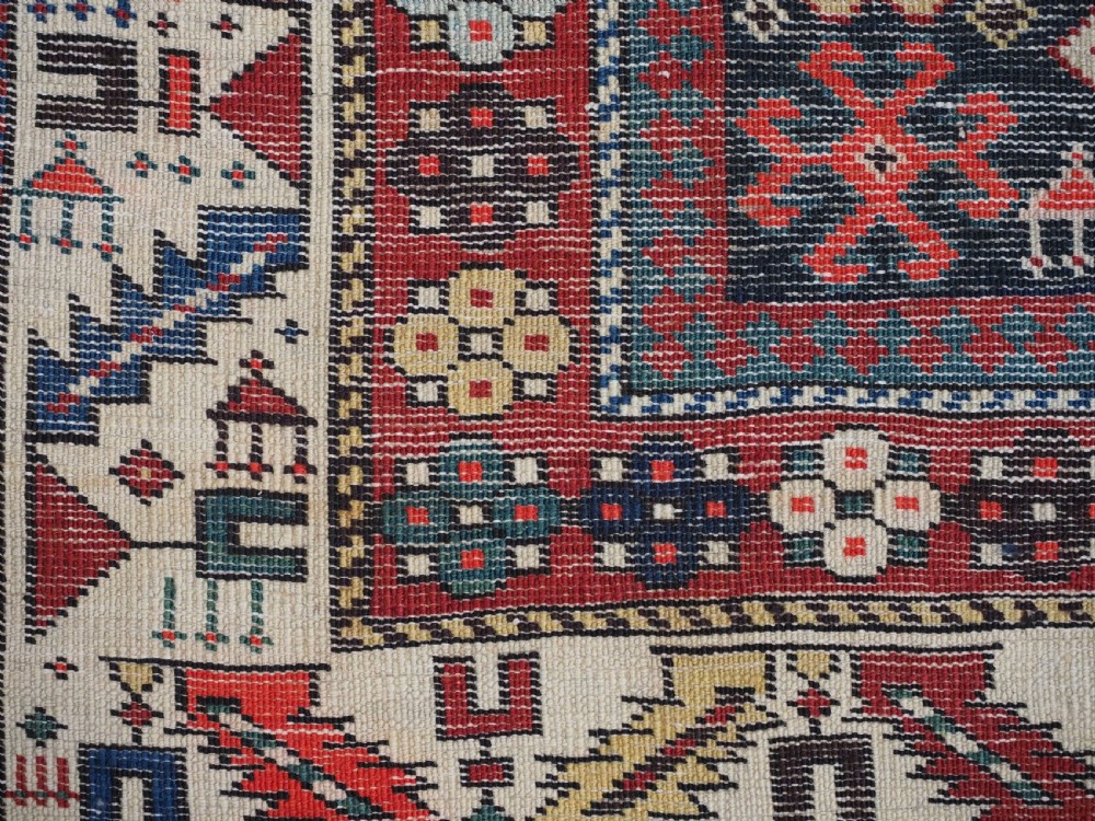 An antique long Caucasian runner rug featuring a dark navy field filled with multi-coloured hooked diamond medallions and detailed geometric borders. View XIII