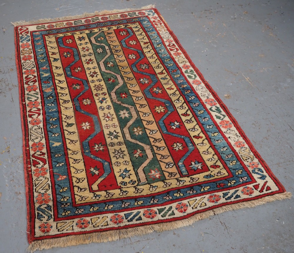 An antique hand-knotted Turkish Konya region wool rug featuring vertical geometric bands in red, blue, green, and cream with star and zig-zag motifs. View II