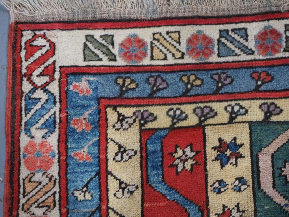 An antique hand-knotted Turkish Konya region wool rug featuring vertical geometric bands in red, blue, green, and cream with star and zig-zag motifs. View VI