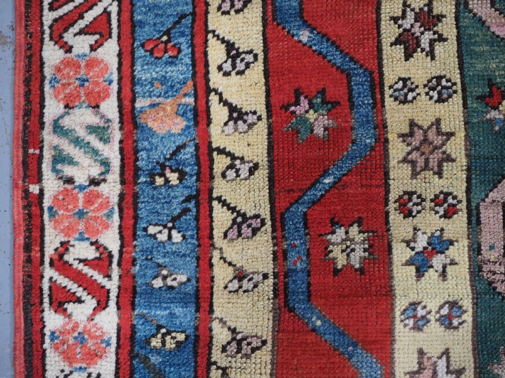 An antique hand-knotted Turkish Konya region wool rug featuring vertical geometric bands in red, blue, green, and cream with star and zig-zag motifs. View VII