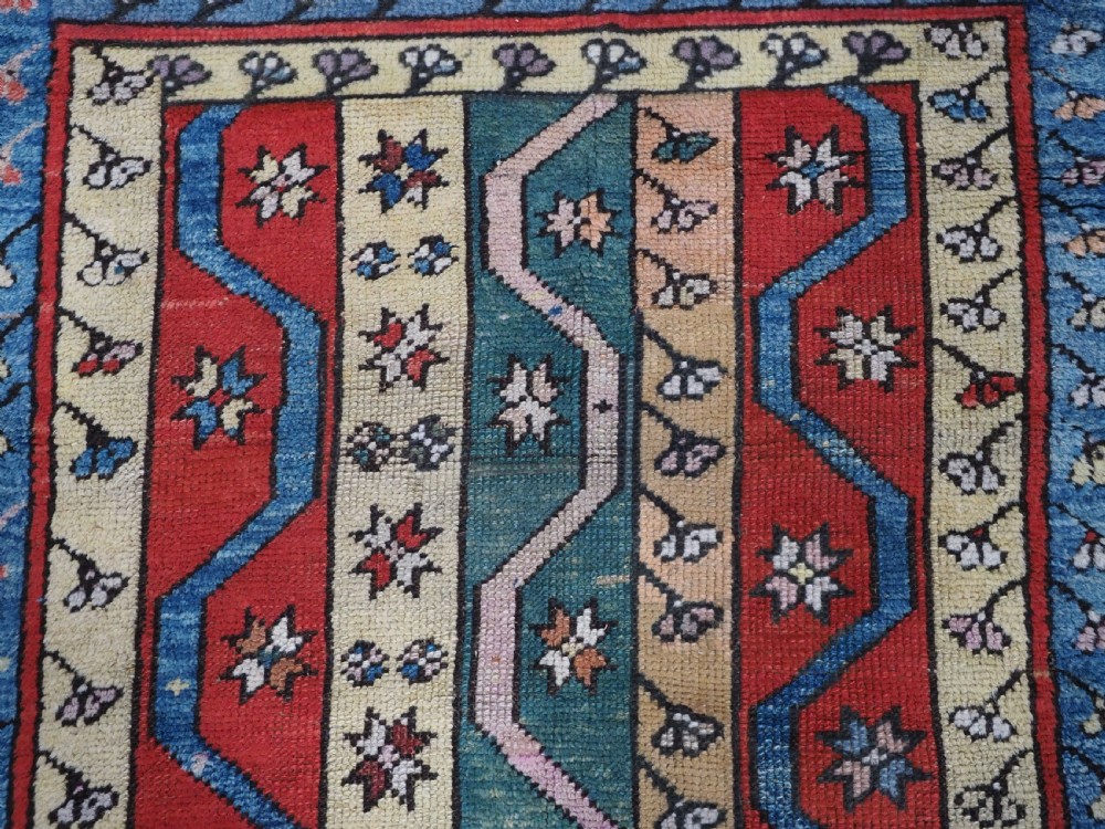 An antique hand-knotted Turkish Konya region wool rug featuring vertical geometric bands in red, blue, green, and cream with star and zig-zag motifs. View VIII