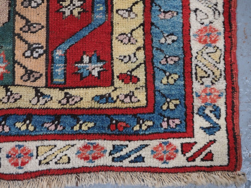 An antique hand-knotted Turkish Konya region wool rug featuring vertical geometric bands in red, blue, green, and cream with star and zig-zag motifs. View XI