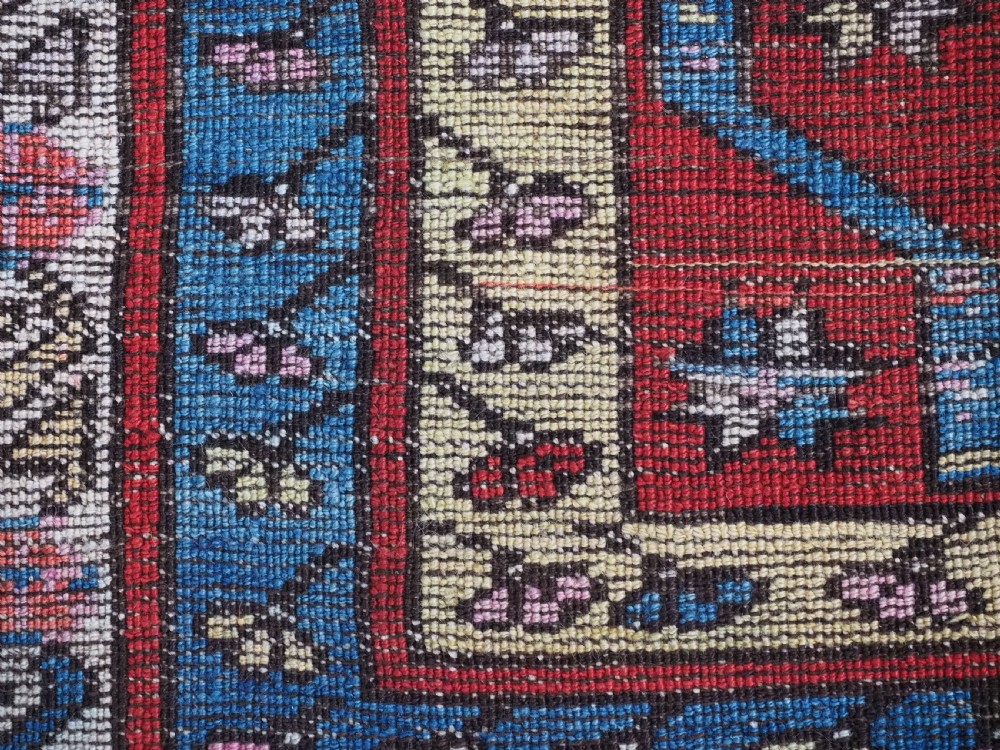 An antique hand-knotted Turkish Konya region wool rug featuring vertical geometric bands in red, blue, green, and cream with star and zig-zag motifs. View XII