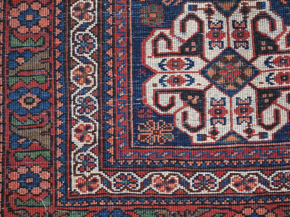 An antique hand-knotted Abadeh wool rug featuring a central diamond medallion, terracotta red field, and navy blue borders with intricate tribal geometric patterns. View XIV