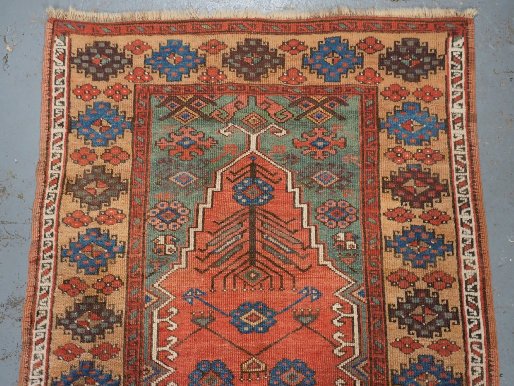 An antique hand-knotted Turkish Konya prayer rug featuring a stepped central red niche surrounded by green, blue, and ochre geometric motifs. View III