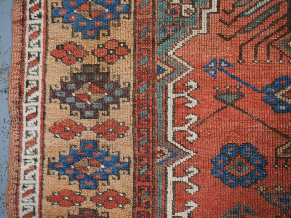 An antique hand-knotted Turkish Konya prayer rug featuring a stepped central red niche surrounded by green, blue, and ochre geometric motifs. View V