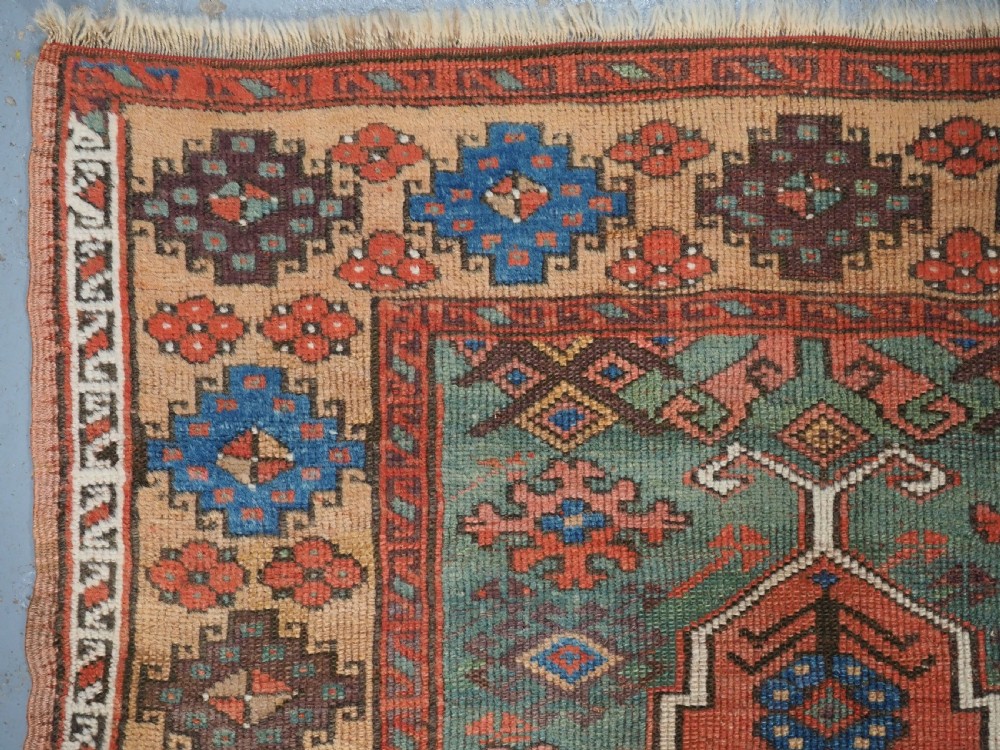 An antique hand-knotted Turkish Konya prayer rug featuring a stepped central red niche surrounded by green, blue, and ochre geometric motifs. View VI
