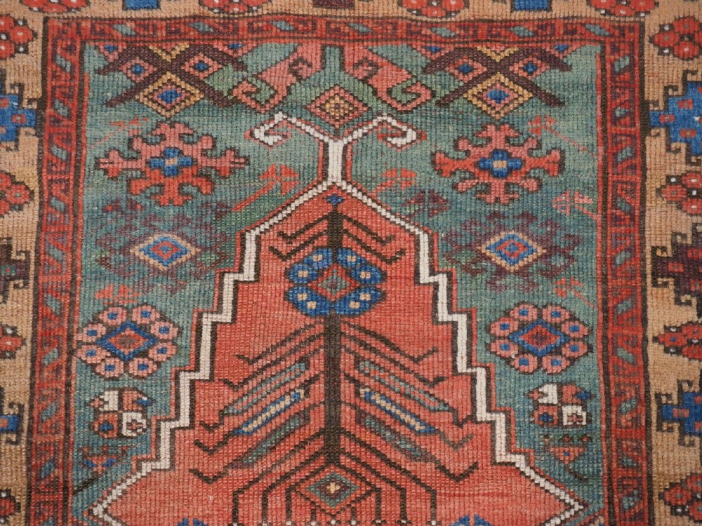An antique hand-knotted Turkish Konya prayer rug featuring a stepped central red niche surrounded by green, blue, and ochre geometric motifs. View VII