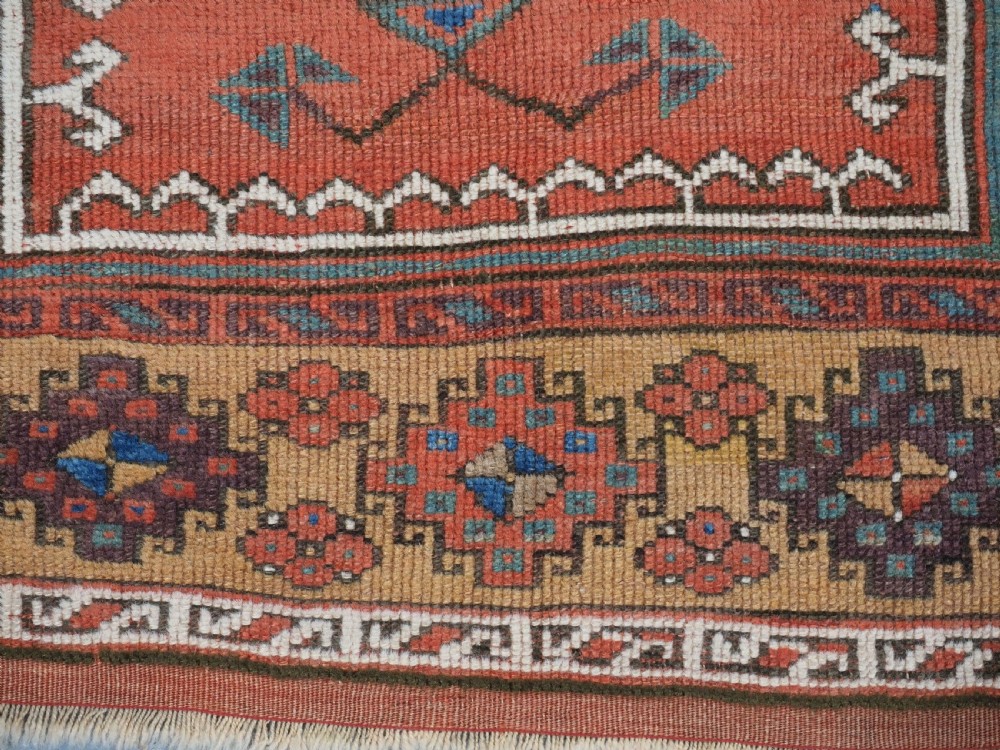 An antique hand-knotted Turkish Konya prayer rug featuring a stepped central red niche surrounded by green, blue, and ochre geometric motifs. View IX