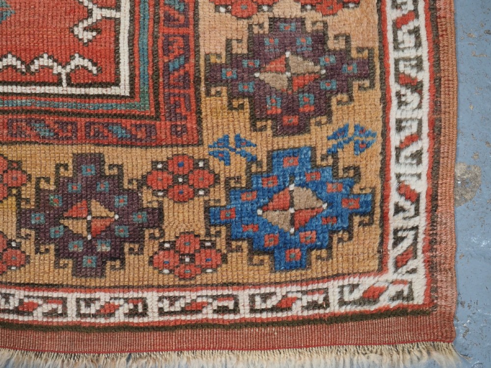 An antique hand-knotted Turkish Konya prayer rug featuring a stepped central red niche surrounded by green, blue, and ochre geometric motifs. View X