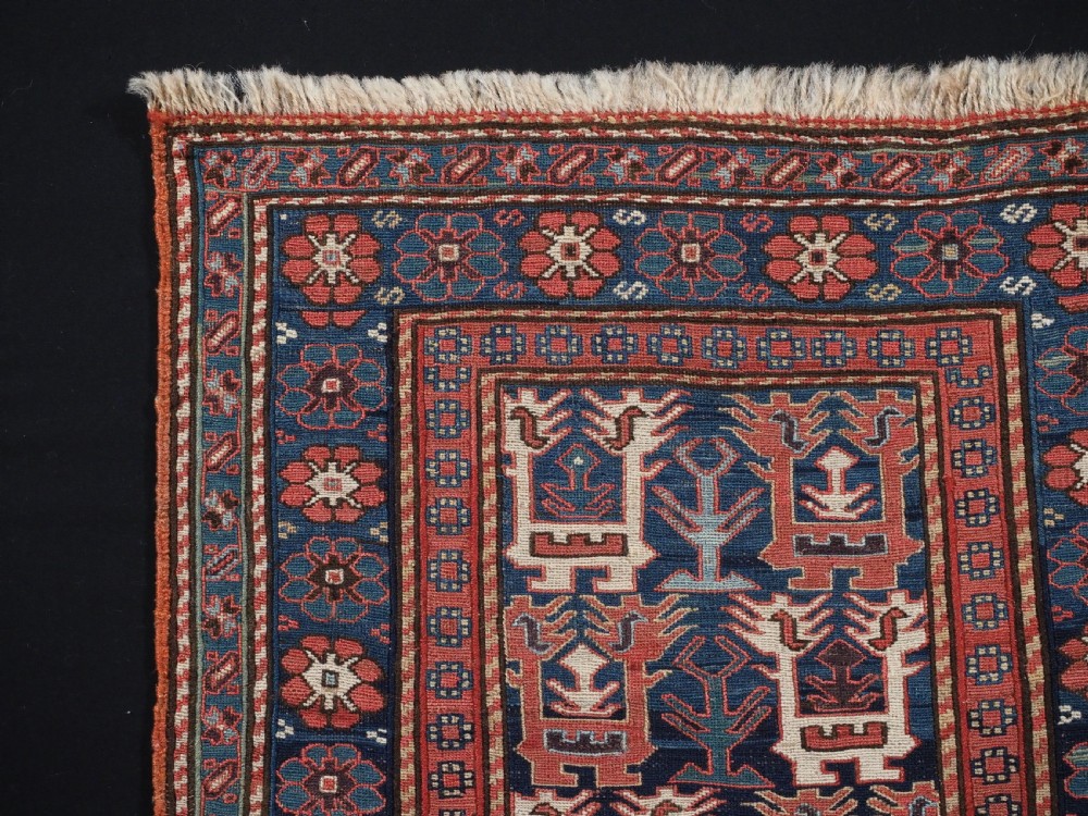 A square antique woven wool Shahsavan Soumak textile panel displaying geometric dragon and bird motifs on a dark navy background framed by red floral borders. View II