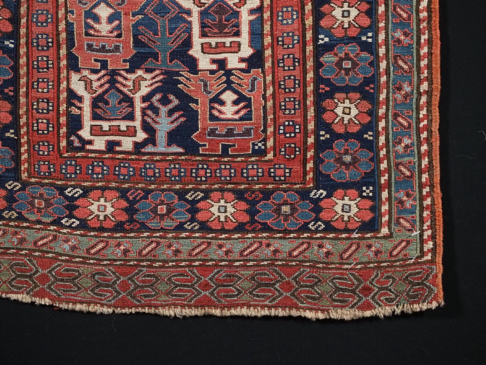 A square antique woven wool Shahsavan Soumak textile panel displaying geometric dragon and bird motifs on a dark navy background framed by red floral borders. View VI