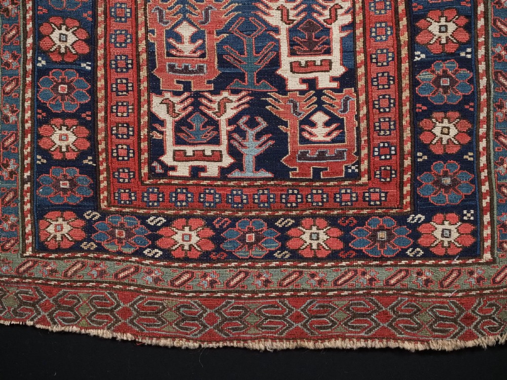 A square antique woven wool Shahsavan Soumak textile panel displaying geometric dragon and bird motifs on a dark navy background framed by red floral borders. View VII