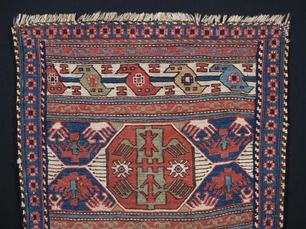 A square antique Shahsevan Soumak woven wool panel featuring central geometric octagonal medallions flanked by bird and dragon motifs in shades of terracotta red, blue, and ivory. View II