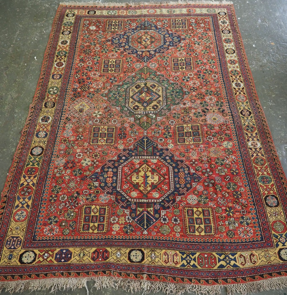An antique Caucasian flatweave Soumak rug featuring three large geometric medallions on a red field framed by a patterned yellow border.