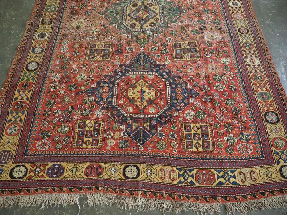 An antique Caucasian flatweave Soumak rug featuring three large geometric medallions on a red field framed by a patterned yellow border. View V