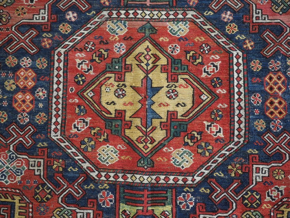 An antique Caucasian flatweave Soumak rug featuring three large geometric medallions on a red field framed by a patterned yellow border. View XII