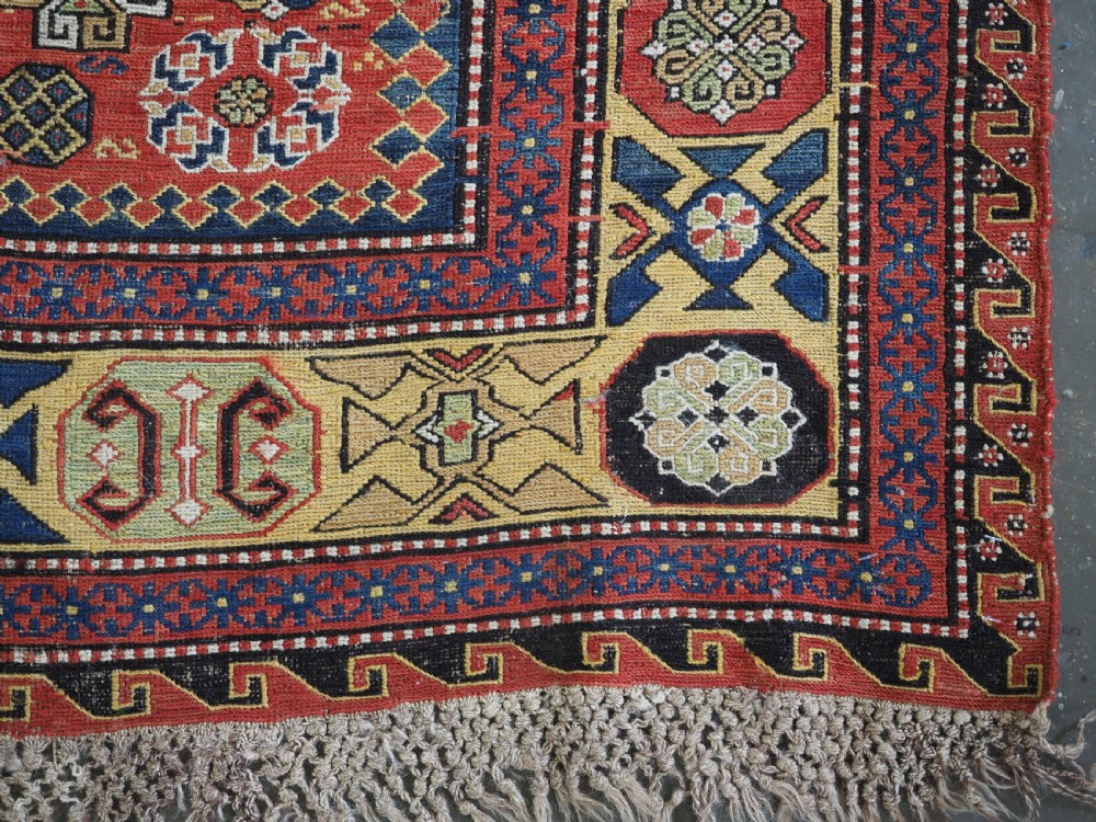 An antique Caucasian flatweave Soumak rug featuring three large geometric medallions on a red field framed by a patterned yellow border. View XV