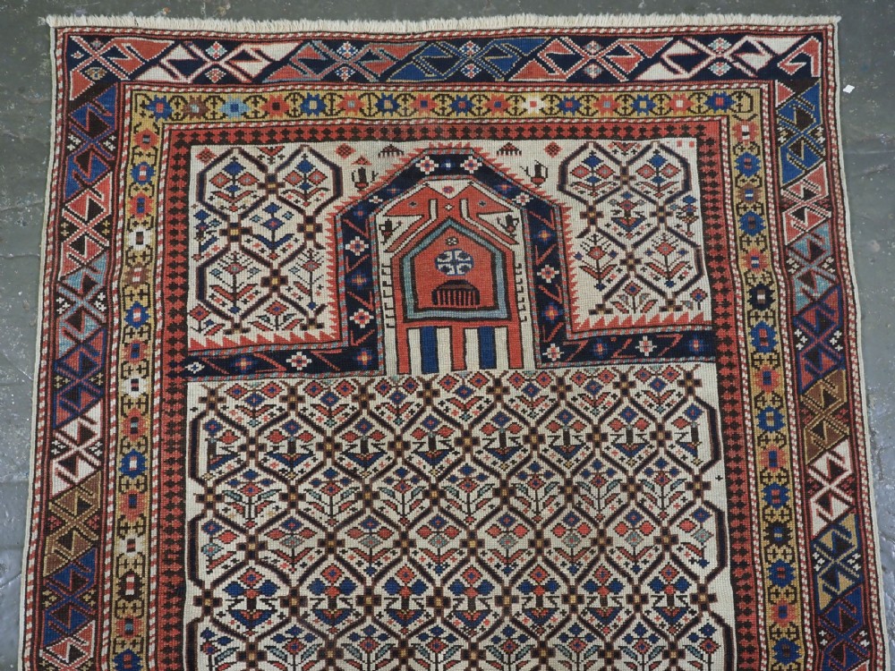 An antique Caucasian Shirvan wool prayer rug featuring an ivory field covered in a geometric floral lattice motif, enclosed by a multi-bordered frame and a stepped prayer arch at the top. View II