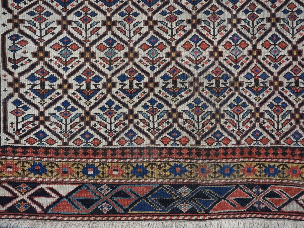 An antique Caucasian Shirvan wool prayer rug featuring an ivory field covered in a geometric floral lattice motif, enclosed by a multi-bordered frame and a stepped prayer arch at the top. View XI
