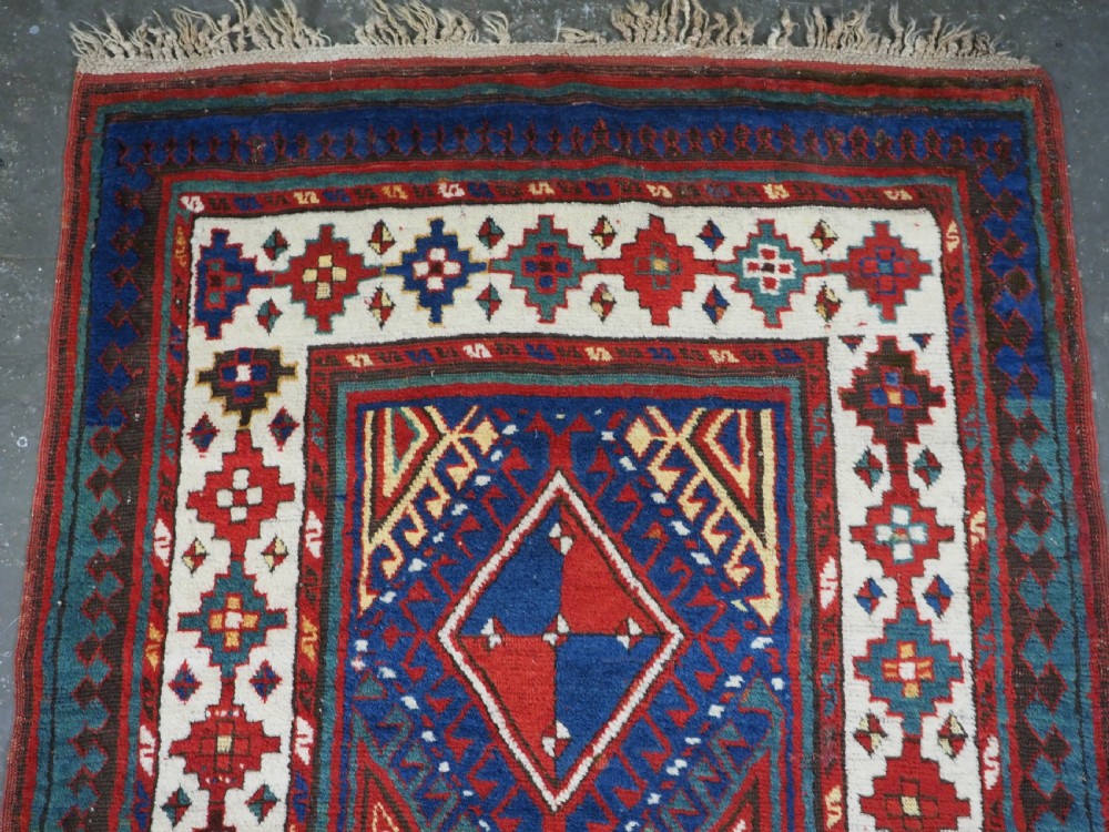 An antique Caucasian Moghan Kazak wool runner rug with repeating diamond hooked medallions on a deep blue field and geometric borders. View II