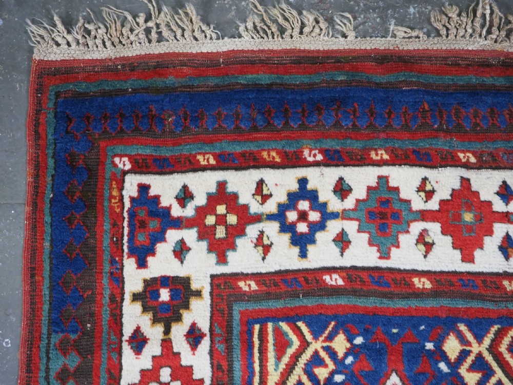 An antique Caucasian Moghan Kazak wool runner rug with repeating diamond hooked medallions on a deep blue field and geometric borders. View VI