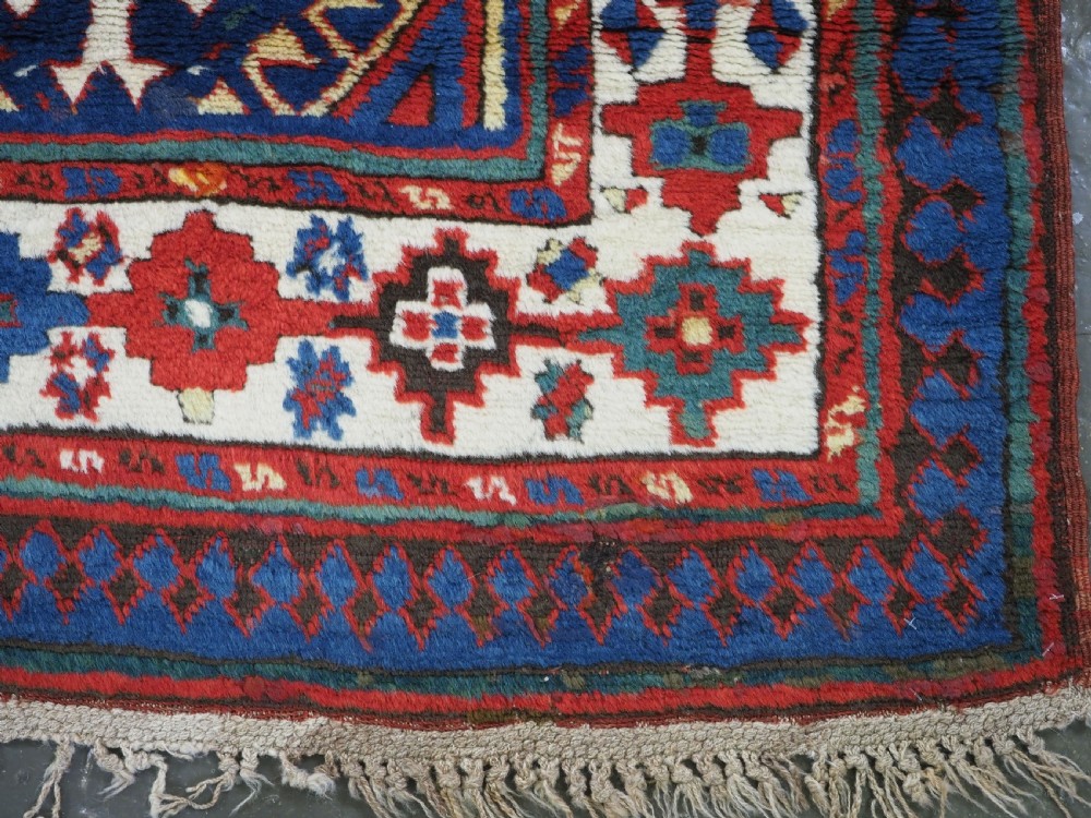 An antique Caucasian Moghan Kazak wool runner rug with repeating diamond hooked medallions on a deep blue field and geometric borders. View XII
