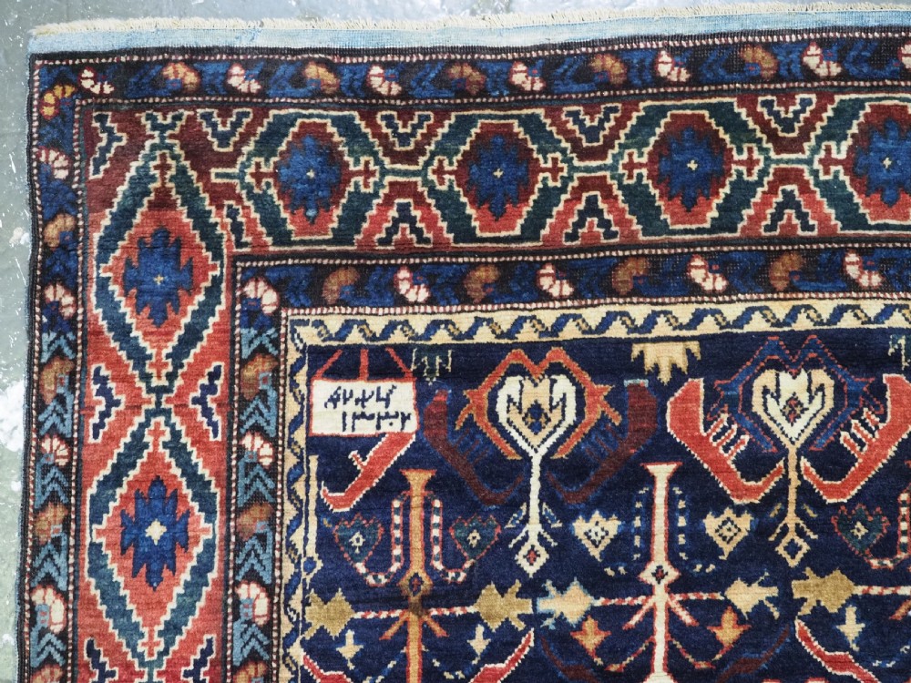 An antique handwoven wool Caucasian Kuba runner featuring dense geometric motifs in red, blue, and cream shades across a long dark navy field. View VIII