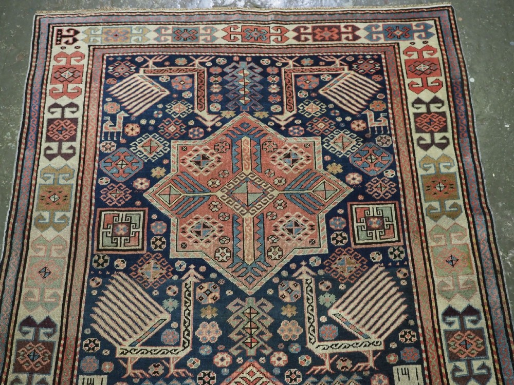 An antique Caucasian Akstafa long rug runner featuring three star medallions and stylized peacock motifs on a dark navy blue field with geometric borders. View III