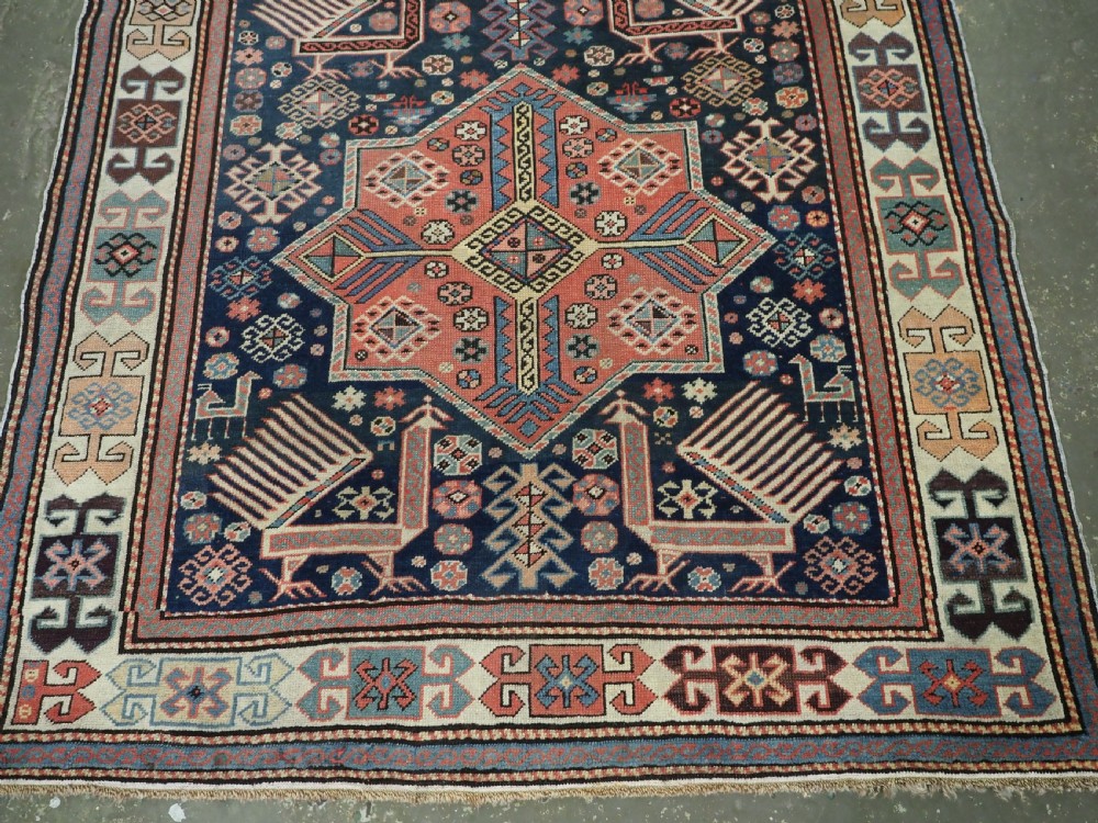 An antique Caucasian Akstafa long rug runner featuring three star medallions and stylized peacock motifs on a dark navy blue field with geometric borders. View VI
