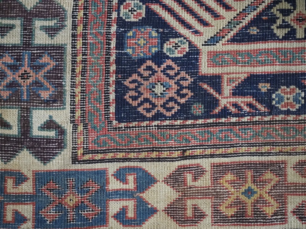 An antique Caucasian Akstafa long rug runner featuring three star medallions and stylized peacock motifs on a dark navy blue field with geometric borders. View X