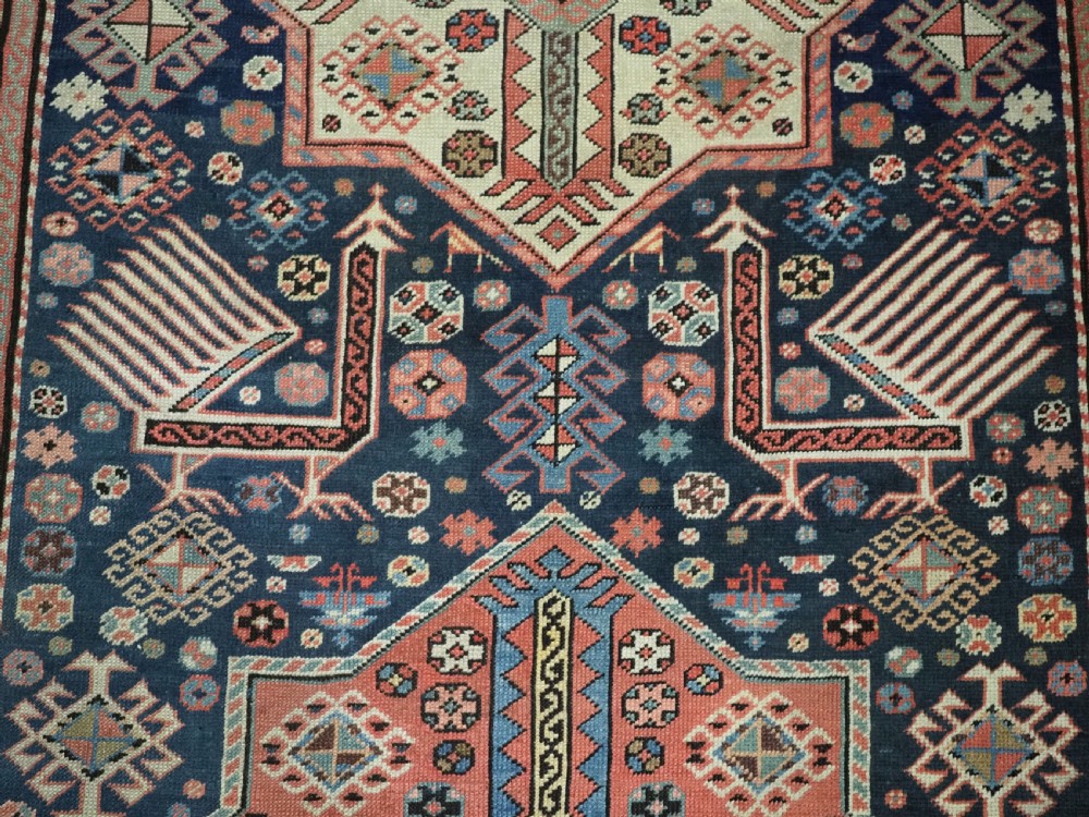 An antique Caucasian Akstafa long rug runner featuring three star medallions and stylized peacock motifs on a dark navy blue field with geometric borders. View XVII