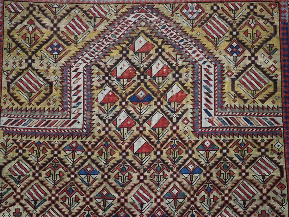 A hand-knotted Caucasian Marasali prayer rug featuring a yellow ground with a prominent pointed mihrab arch, diamond lattice patterns, and geometric borders in red, blue, and brown. View IV