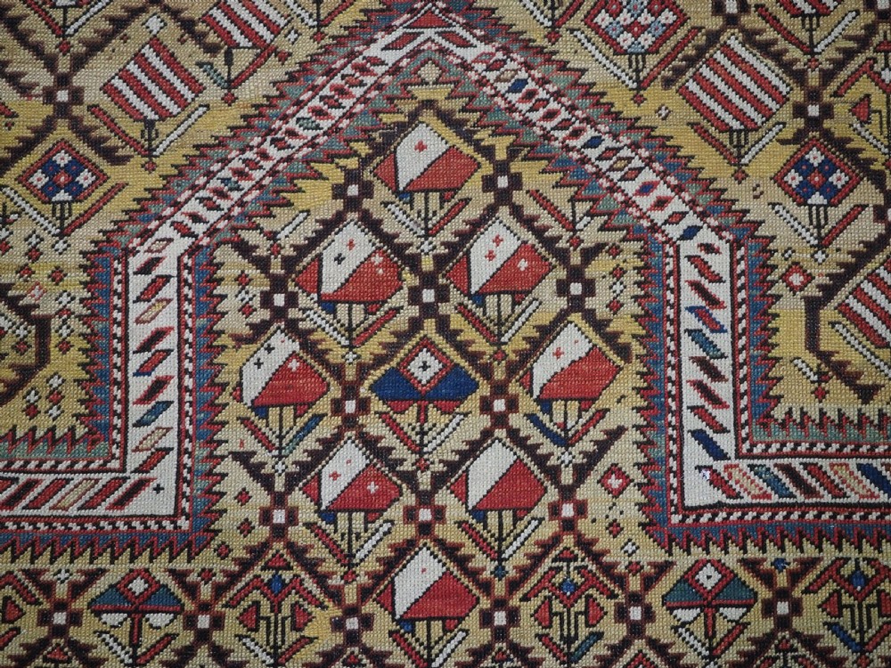 A hand-knotted Caucasian Marasali prayer rug featuring a yellow ground with a prominent pointed mihrab arch, diamond lattice patterns, and geometric borders in red, blue, and brown. View V
