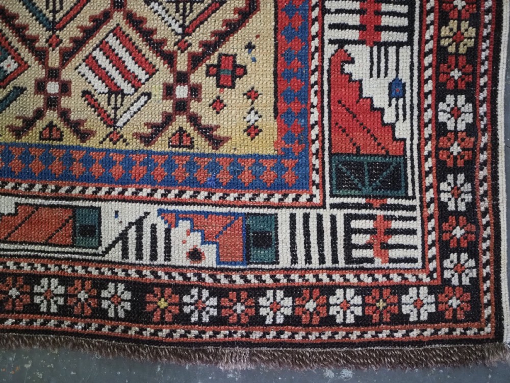 A hand-knotted Caucasian Marasali prayer rug featuring a yellow ground with a prominent pointed mihrab arch, diamond lattice patterns, and geometric borders in red, blue, and brown. View VII