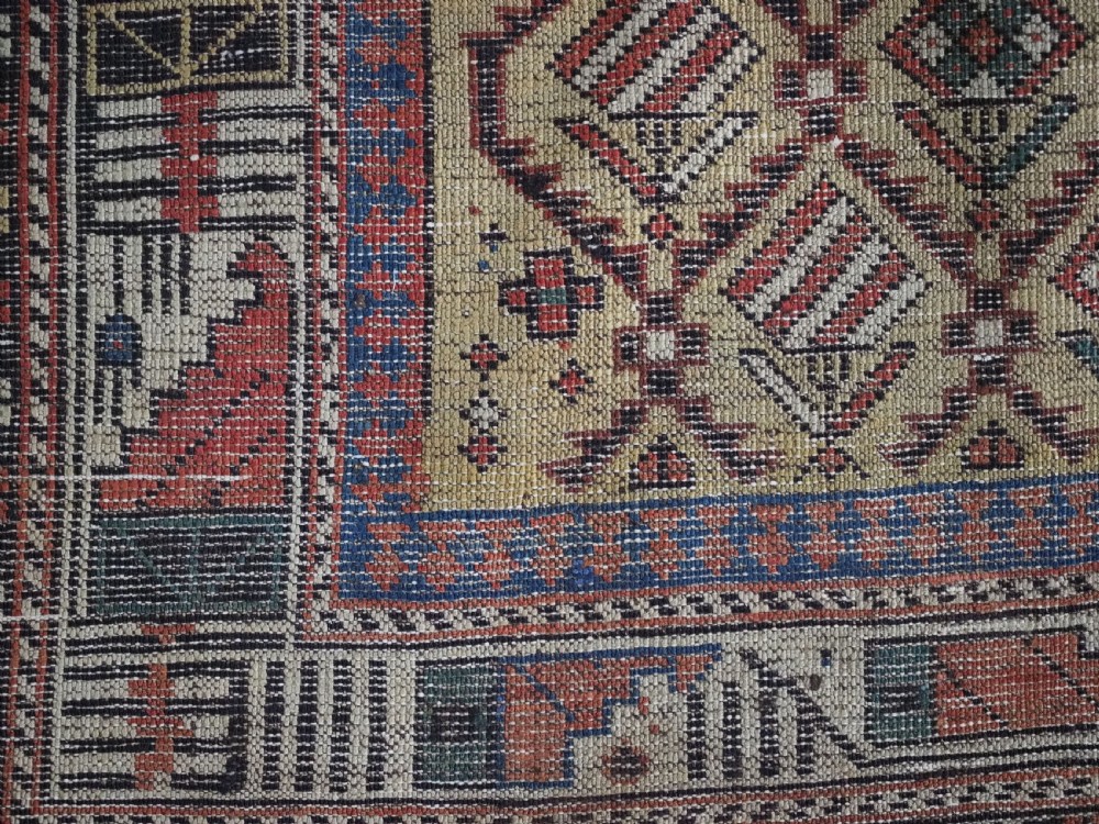 A hand-knotted Caucasian Marasali prayer rug featuring a yellow ground with a prominent pointed mihrab arch, diamond lattice patterns, and geometric borders in red, blue, and brown. View X